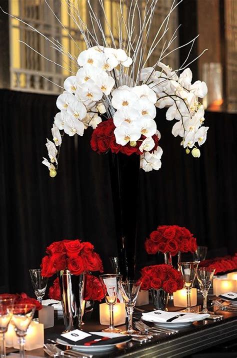 The Centerpiece Is Decorated With Red And White Flowers In Tall Vases