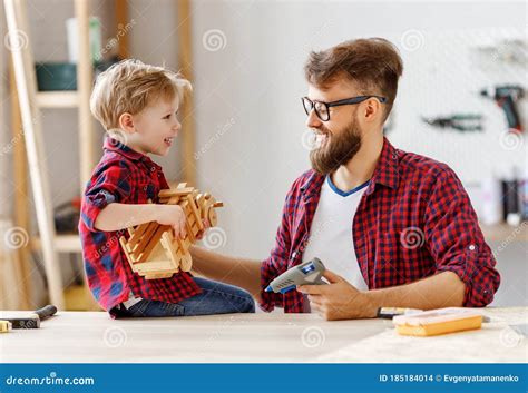 Cheerful Man With Kid Making Wooden Toys In Workshop Stock Photo