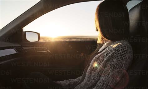 Young Woman Sitting In Passenger Seat Of Car Looking Out Of Window