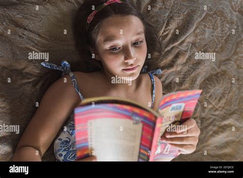 Girl Reading Book While Lying On Bed At Home Stock Photo Alamy