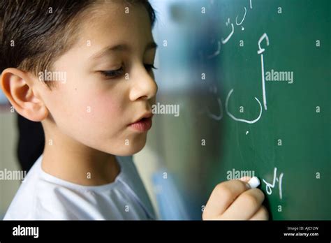 Boy Writing On Blackboard In Classroom Stock Photo Alamy