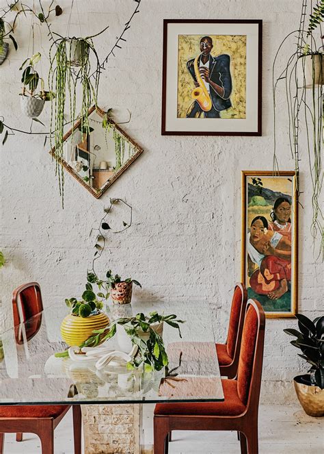A Dining Room Table Surrounded By Potted Plants And Pictures On The