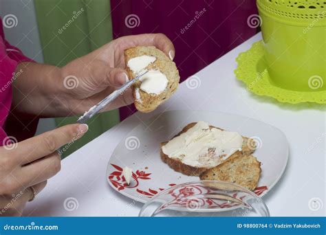 The Woman Is Spreading Butter On Toast For Herself For Breakfast Stock