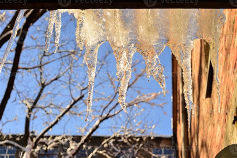 Melting Icicles Hanging Down From Roof With Blue Sky Background Sunny