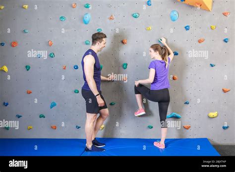 Instructor Teaching Young Woman To Climb Wall In Gym Stock Photo Alamy