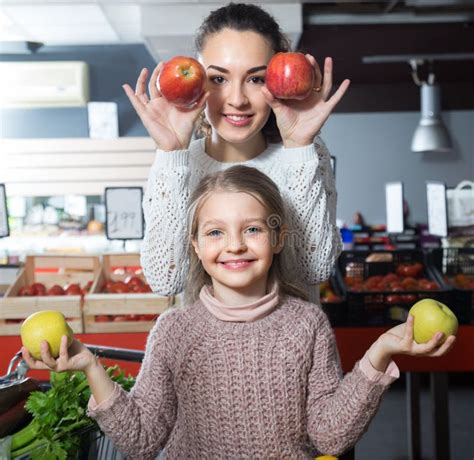 Brunette Female With A Little Girl Considering Apples At Store Stock