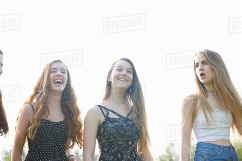 Four teenage girls laughing and chatting in park - Stock Photo - Dissolve