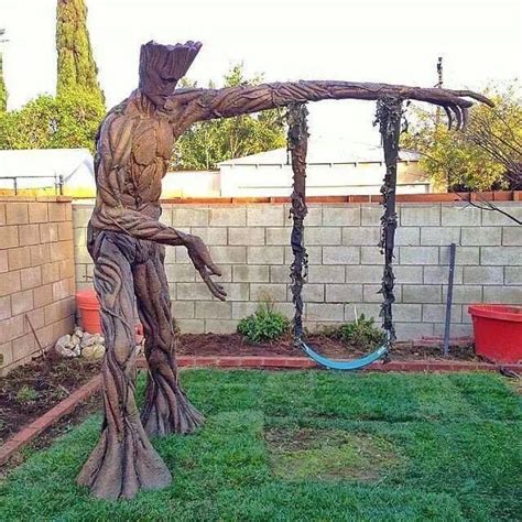A Statue Of A Man Swinging On A Swing Set In A Yard With A Brick Wall