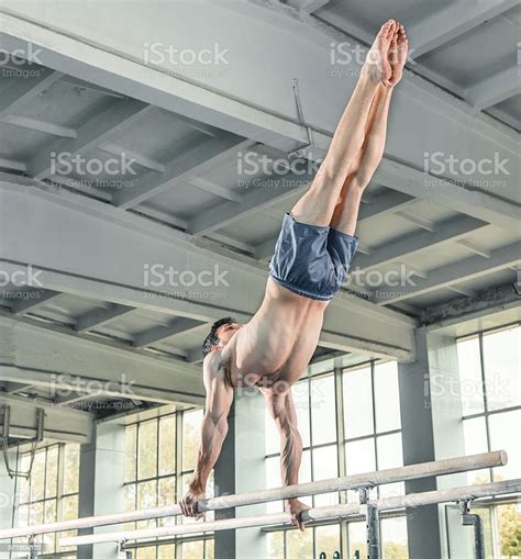 Male Gymnast Performing Handstand On Parallel Bars Stock Photo