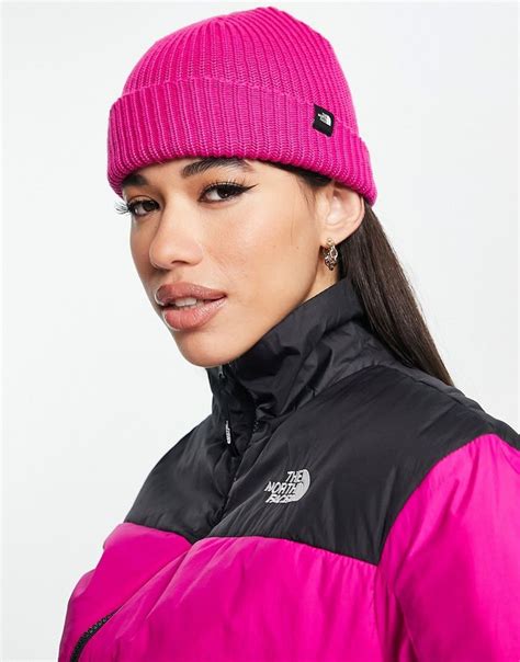 A Woman Wearing A Pink And Black Jacket With The North Face Logo On Her Hat