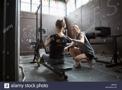 Personal Trainer Guiding Woman Weightlifting Doing Seated Rows In