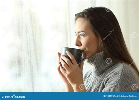 Happy Woman Drinking Coffee Looking Rain Through A Window Stock Photo