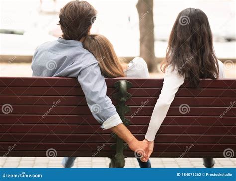 Boyfriend Holding Hands With Girlfriend S Friend Sitting On Bench