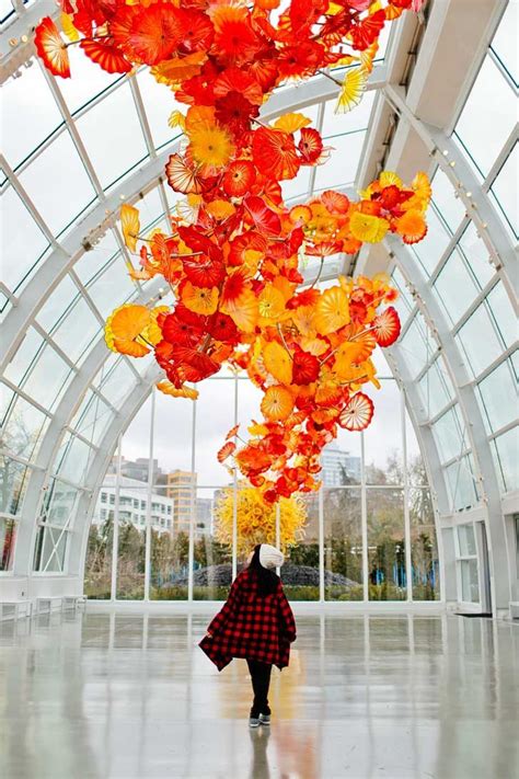 A Person Standing Under A Glass Sculpture In A Building