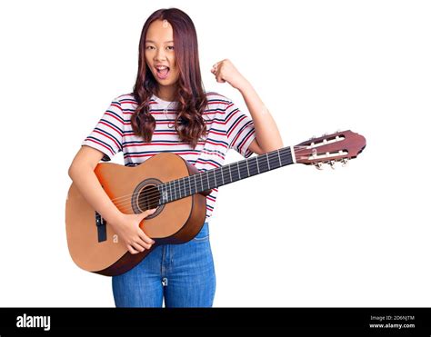 Young Beautiful Chinese Girl Playing Classical Guitar Screaming Proud