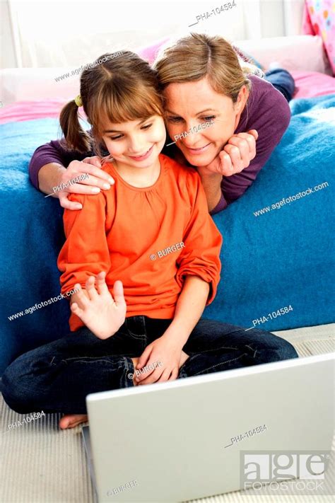 7 Years Old Girl With Her Mother Using Laptop Computer Stock Photo