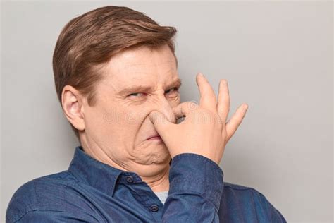 Portrait Of Mature Man Pinching His Nose And Grimacing From Disgust