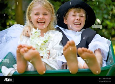 Junge Und Ein Mädchen Tragen Braut Und Bräutigam Kostüme Sitzen In Einer Schubkarre Lachen
