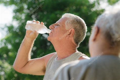 Seniors Drinking Water After Fitness In Park — Stock Photo © Diego