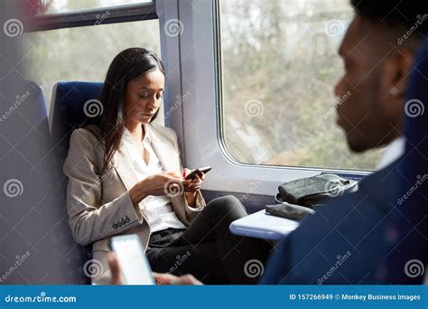 business passengers sitting in train commuting to work looking at mobile phones stock image