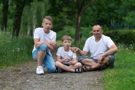 A Father With His Sons Sits On The Ground Stock Image Image Of