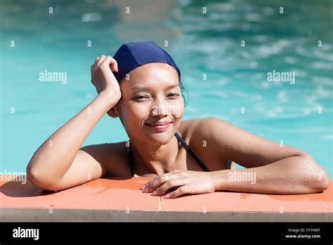 Girl In Bikini And Swimming Cap Leaning On The Edge Of The Pool Stock