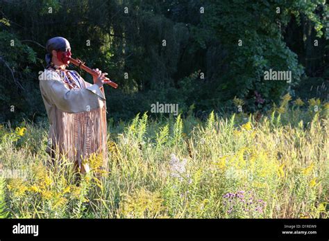 A Native American Indian Man Playing A Wooden Flute Outside In Nature