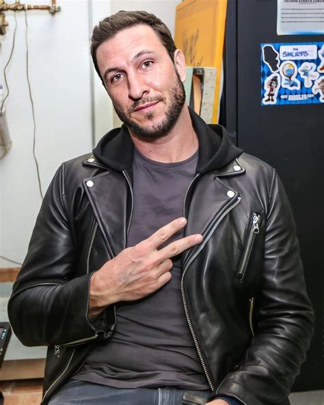 A Man Wearing A Black Leather Jacket Standing In Front Of A