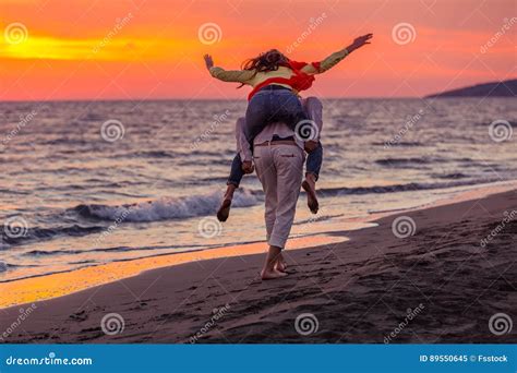 A Guy Carrying A Girl On His Back At The Beach Outdoors Stock Image