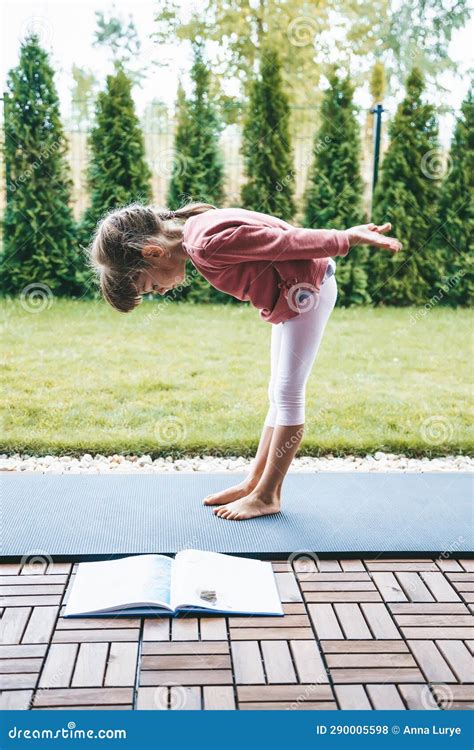 Little Girl Bending Over While Practicing Yoga Outdoors Stock Photo