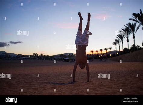 Silhouetted Boy Doing Handstand On Beach At Dusk Stock Photo Alamy