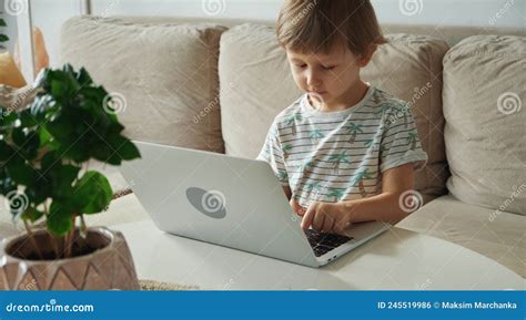 Child Using Laptop Sitting On Sofa At Home Home Schooling Distance