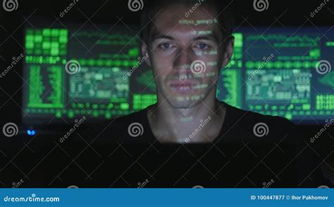 Hacker Programmer Working On A Computer While Green Code Characters Reflect On His Face In A