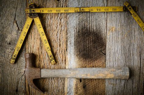 Old Tape Measure And Hammer For Construction On Rustic Wood Back