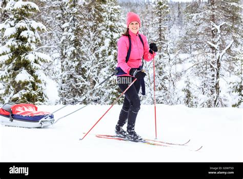 Young Woman Cross Country Skiing With Pull Behind Baby Pulk Sled Stock