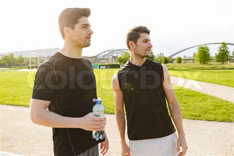 image of two muscular guys drinking water while working out and running at at green park