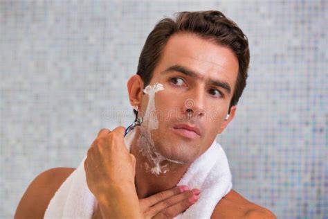 Portrait Of Young Attractive Man Shaving His Beard While Looking In The