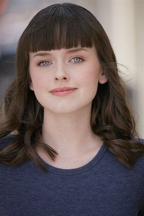 A Close Up Of A Person Wearing A Blue Shirt And Long Brown Hair With Bangs