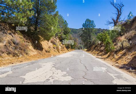 Cracked And Rugged Road Leads Through Wooded Hills In Southern