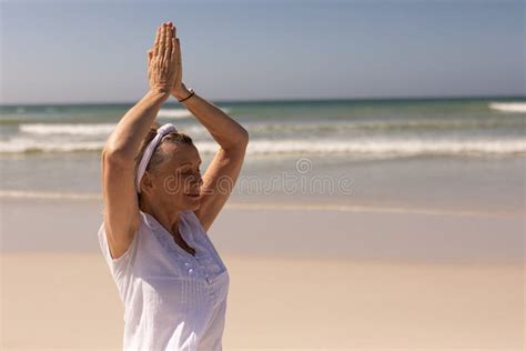 Side View Of Senior Woman Meditating In Prayer Position At Beach Stock