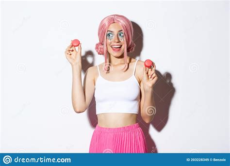 Portrait Of Silly Beautiful Caucasian Girl In Pink Anime Wig Showing Macaroons And Looking