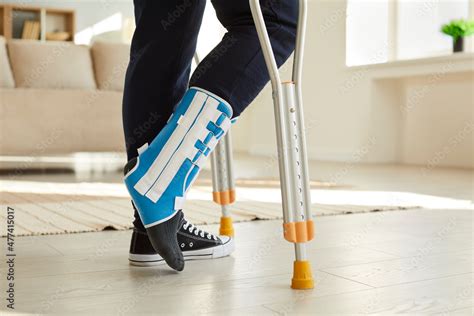 Close Up Leg Of Man Walking With Crutches In Ankle Brace With Support