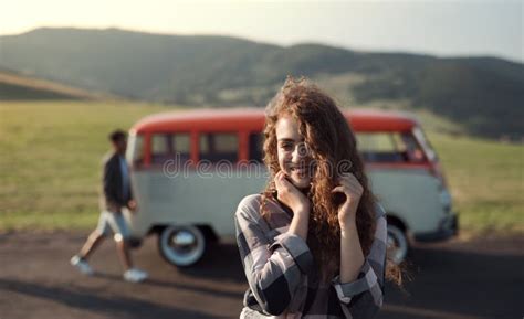 A Young Girl On A Roadtrip Through Countryside Standing By A Minivan