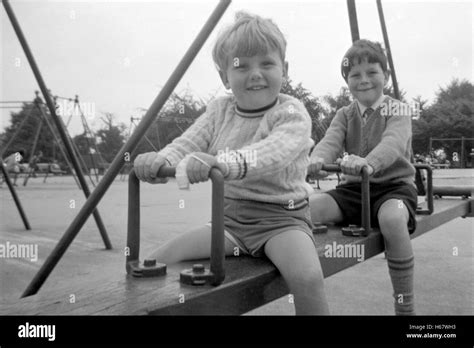 Young Boys On A Bench Swing At A Public Park In The 1960s Uk Stock