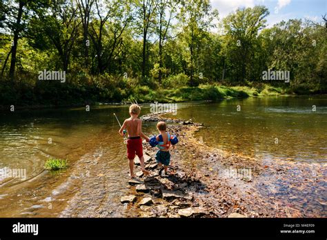 Two Boys Crossing A River To Go Fishing Stock Photo Alamy