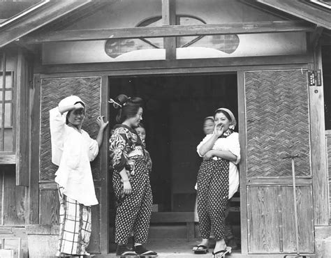 Three Women Standing In Front Of A Wooden Building