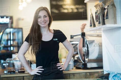 Portrait Of Young Female Waitress Behind Kitchen Counter In Cafe