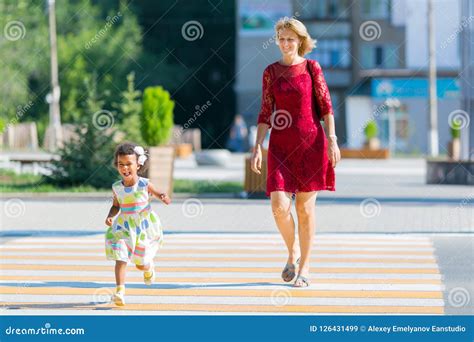 The Child Runs Away From The Mother On The Pedestrian Crossing Stock