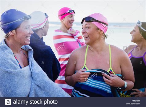 Female Open Water Swimmers Talking And Drying Off With Towels On Beach
