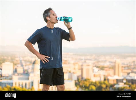 Mixed Race Man Drinking Water Bottle On Urban Hilltop Stock Photo Alamy